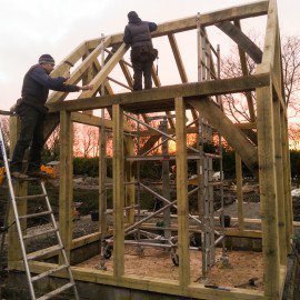 carpenters fitting roof beans to new oak framed garden room